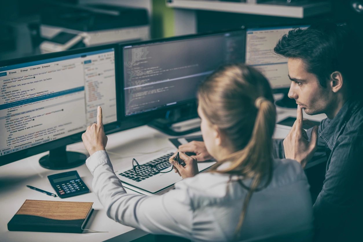 2 people looking at some code on a computer screen.